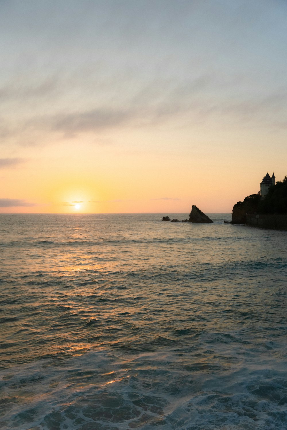 the sun is setting over the ocean with a small island in the distance