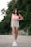 a woman in a pink top is walking down the street