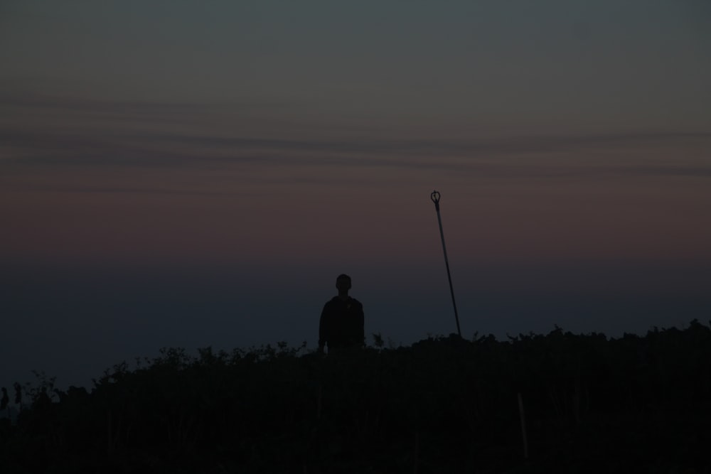 Un hombre parado en la cima de una colina junto a una farola