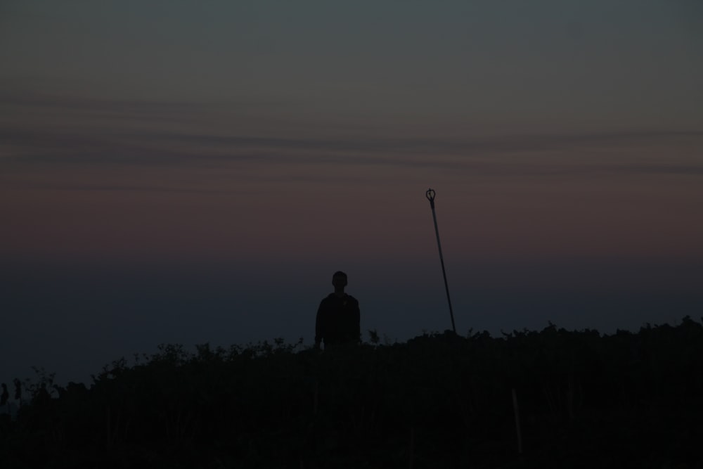 Un homme debout au sommet d’une colline à côté d’un lampadaire