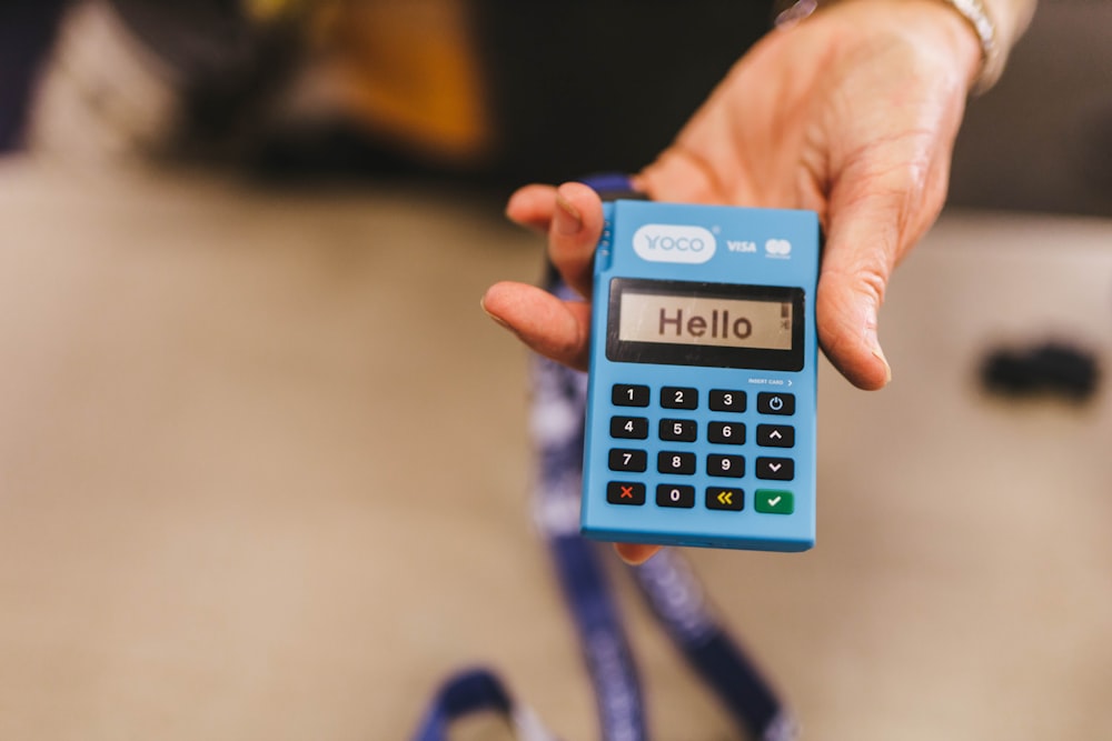 une personne tenant une calculatrice bleue dans sa main