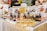 A market stall displaying an array of natural hair and skincare products, including bottles, jars, and soap bars. Promotional signs indicate offerings such as natural hair treatments, sprays, and soap. The products are neatly arranged on wooden blocks and layered fabric, with a variety of colors and branding labels visible.