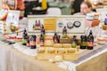 A market stall displaying an array of natural hair and skincare products, including bottles, jars, and soap bars. Promotional signs indicate offerings such as natural hair treatments, sprays, and soap. The products are neatly arranged on wooden blocks and layered fabric, with a variety of colors and branding labels visible.