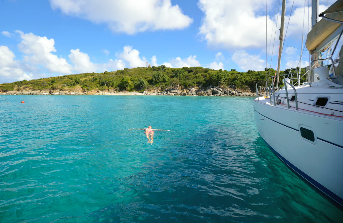 A swimmer in clear water beside a boat