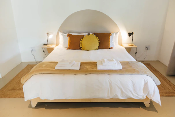 A cozy bedroom scene featuring neatly folded black and white bedsheets and plush towels arranged on a minimalist bed.