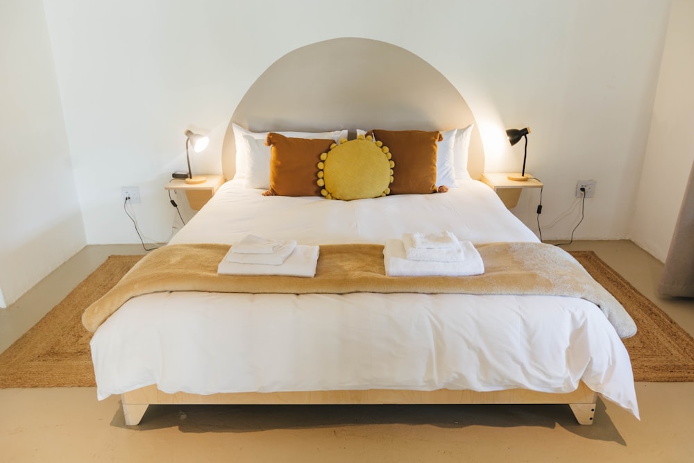 a bed with white sheets and brown pillows