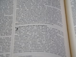 A close-up shot of an open book displaying text on both visible pages, with focus on the text about Ezekiel's call to be a prophet. The text is printed in two columns, and the alignment of the words is neat and justified.