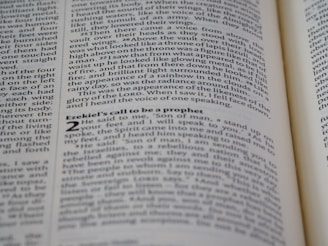 A close-up shot of an open book displaying text on both visible pages, with focus on the text about Ezekiel's call to be a prophet. The text is printed in two columns, and the alignment of the words is neat and justified.