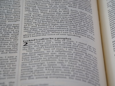 A close-up shot of an open book displaying text on both visible pages, with focus on the text about Ezekiel's call to be a prophet. The text is printed in two columns, and the alignment of the words is neat and justified.