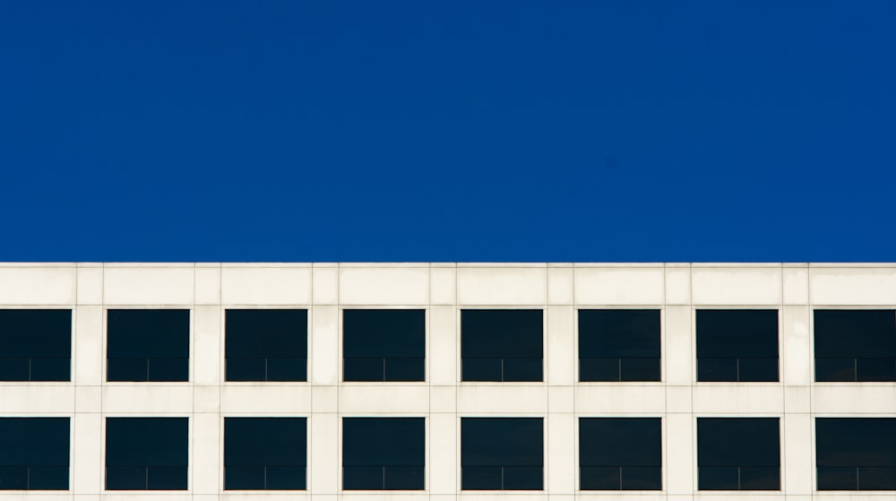 an airplane flying over a white building with lots of windows