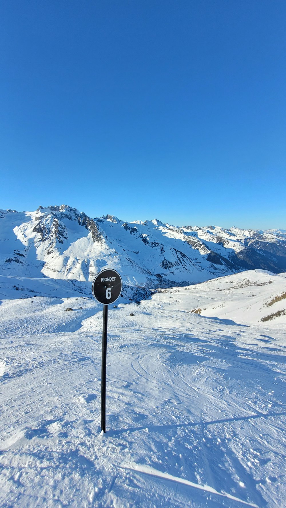 a sign in the snow with mountains in the background