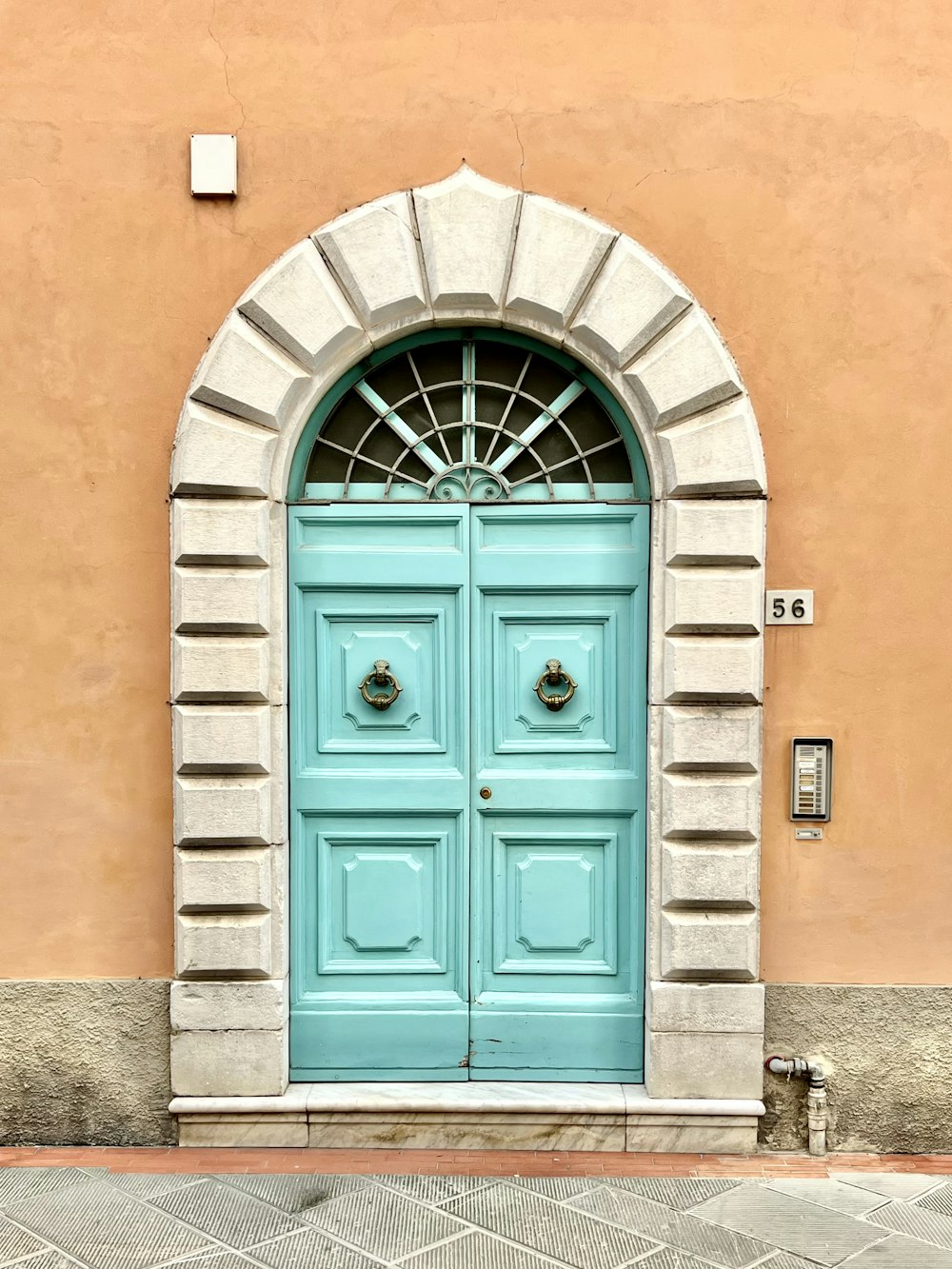 a blue door with a brick arch on the side of a building