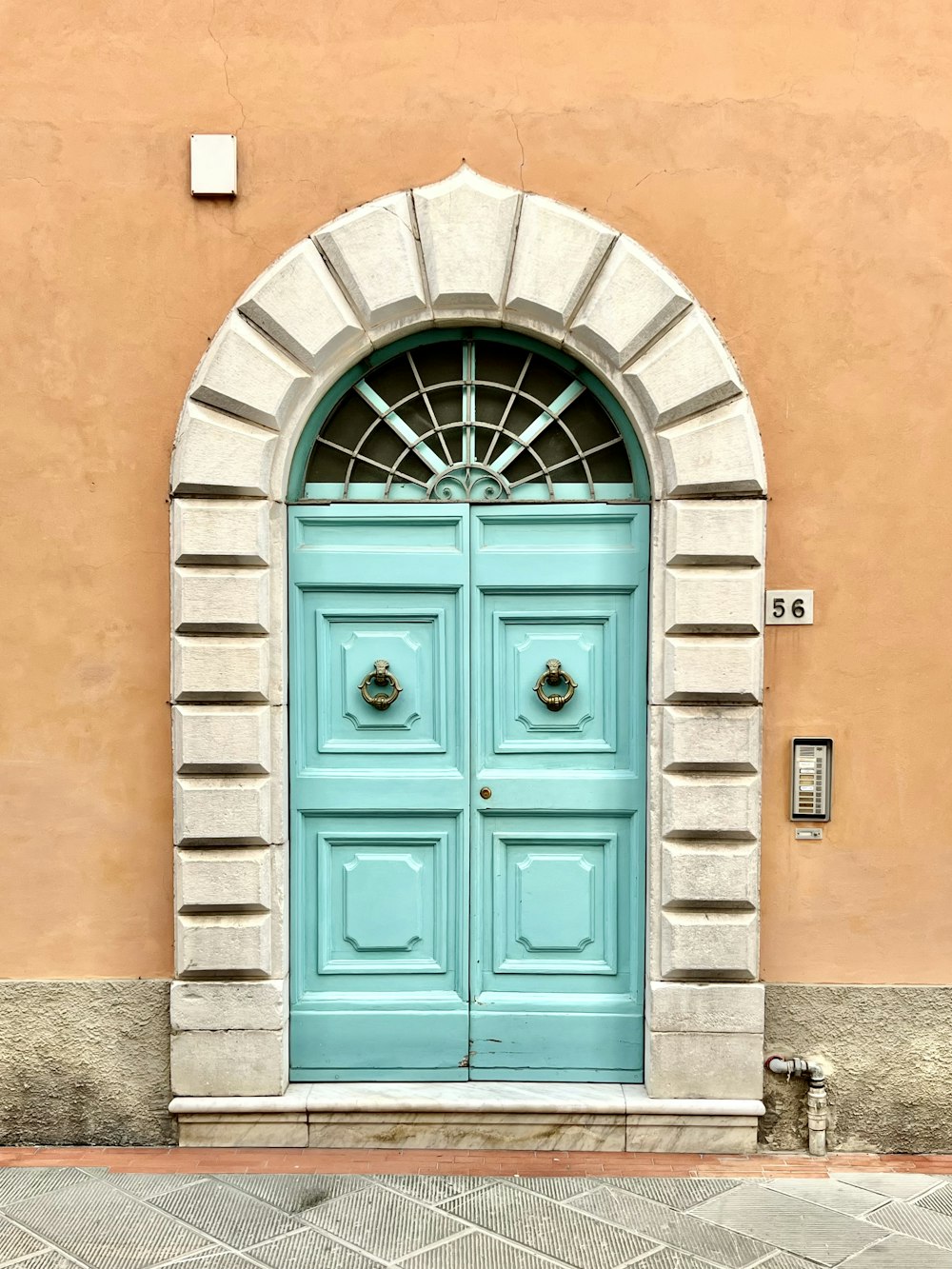 una puerta azul con un arco de ladrillo en el costado de un edificio