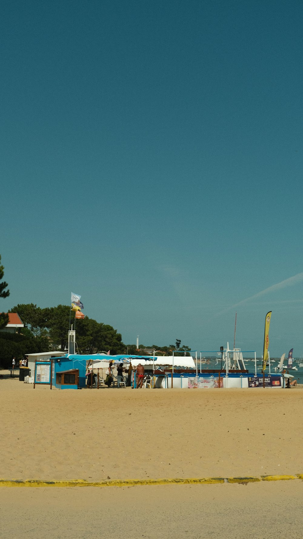 a sandy beach with a blue boat in the distance