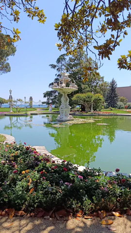 Outdoor garden scene featuring a cement fountain surrounded by greenery