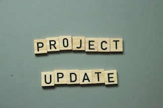 two scrabble tiles spelling project update on a table