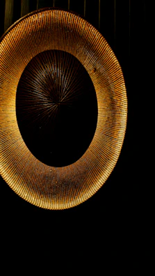 An artistic close-up of a minimalist circular sun emblem rendered with warm ochre and soft gold light.