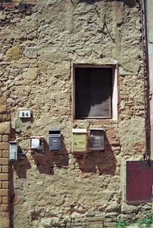 Photo of a rustic brick wall with a small mailbox attached.