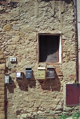 Photo of a rustic brick wall with a small mailbox attached.