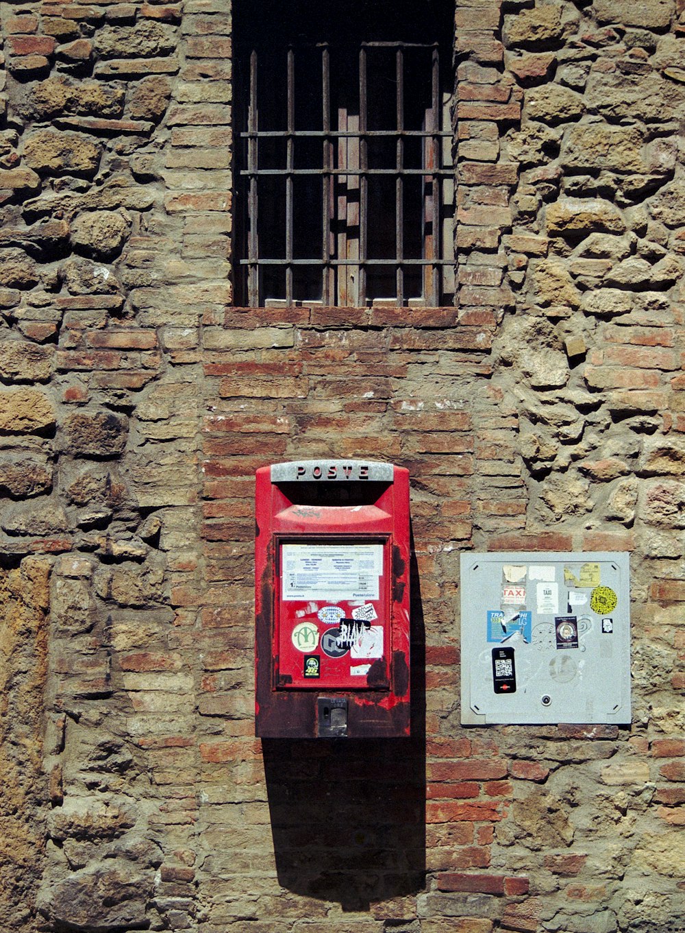 a red mailbox sitting on the side of a brick building