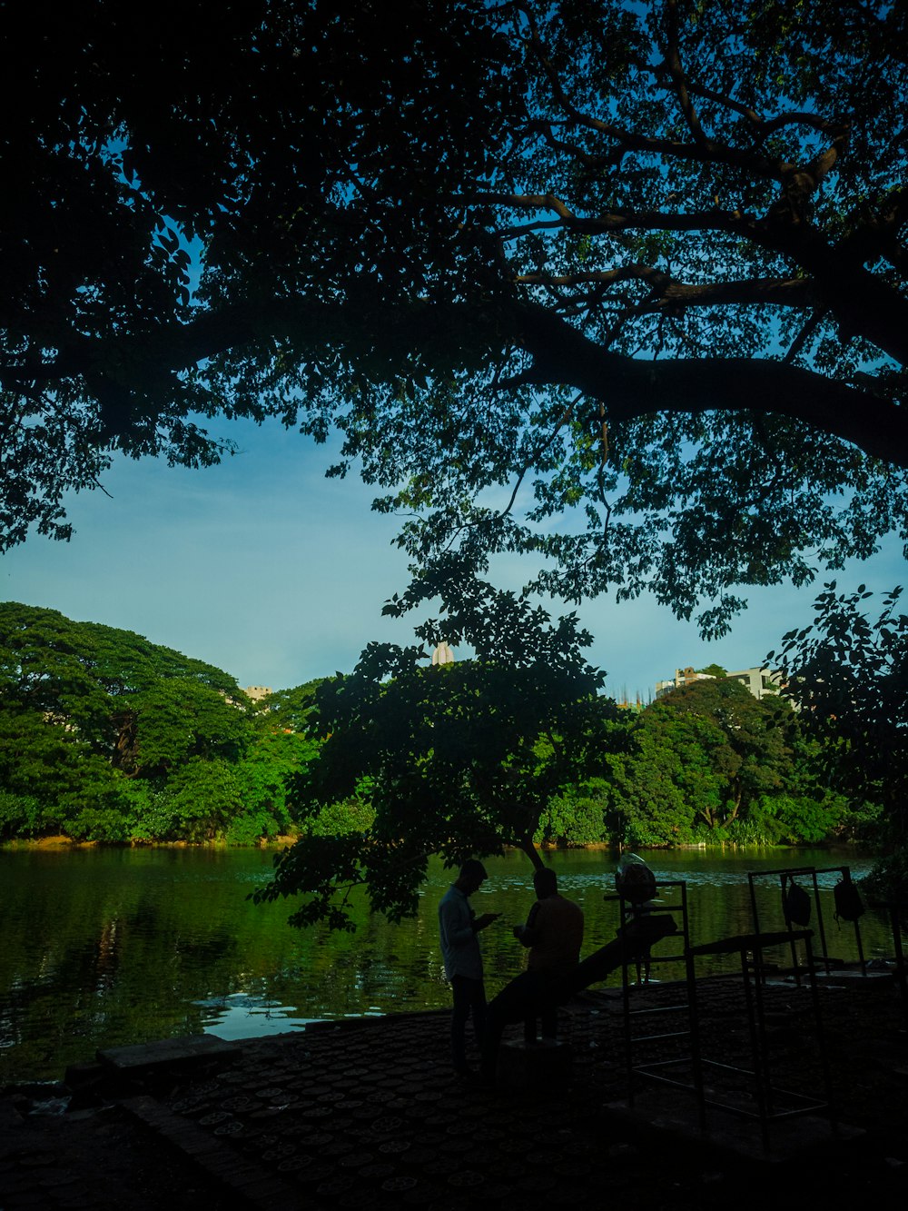 a couple of people sitting on a bench next to a lake