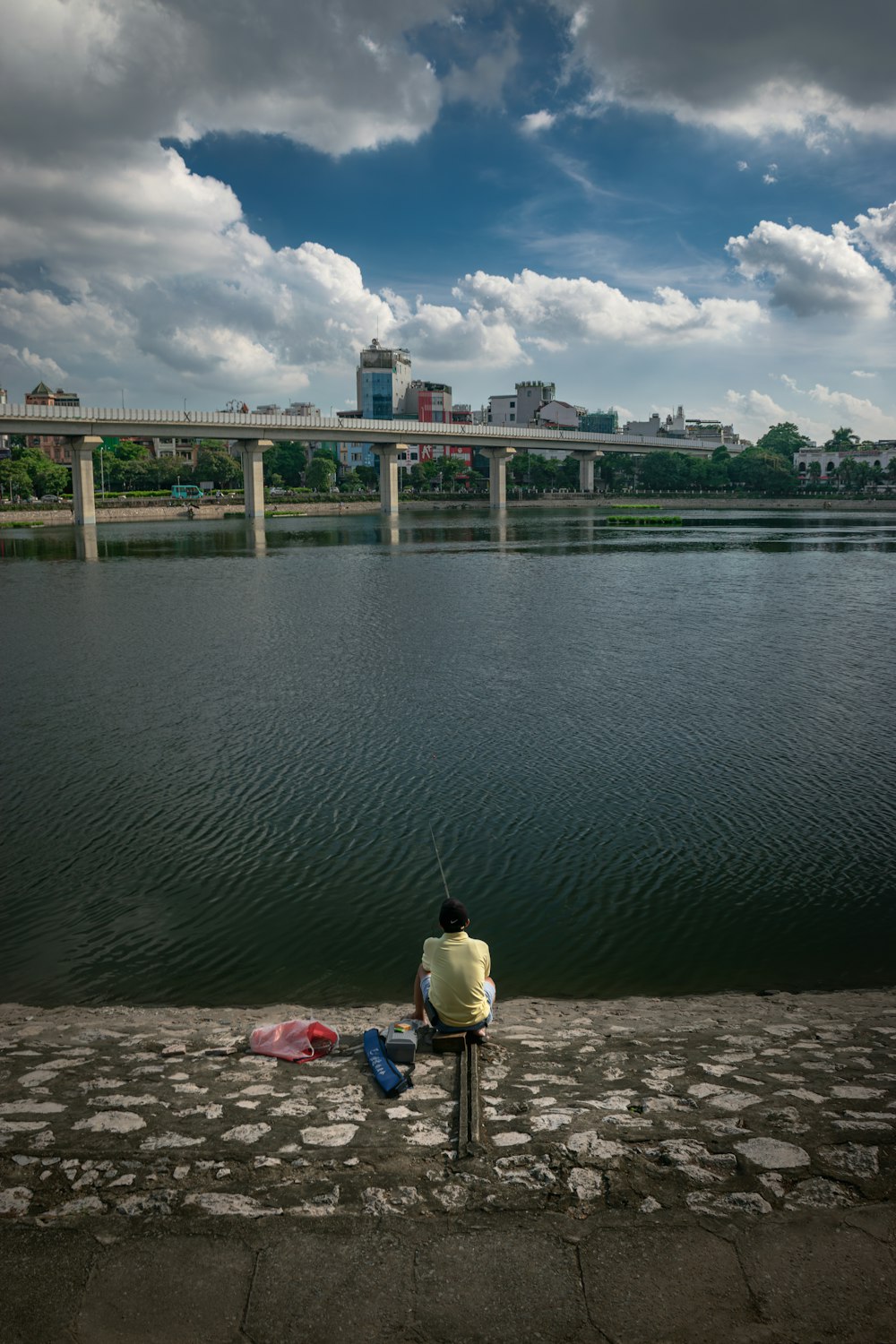 a man sitting on a bench next to a body of water