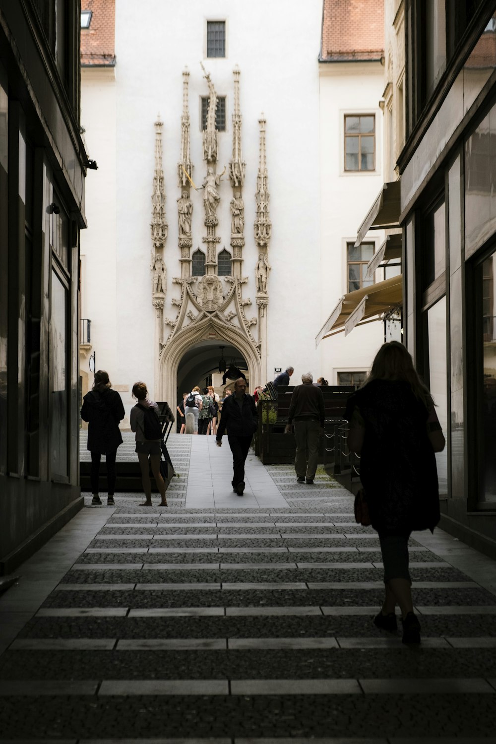 a group of people walking down a street next to tall buildings