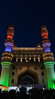 A famous landmark illuminated at night, bustling with tourists.