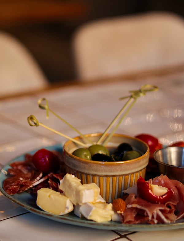 A plate of food with olives, cheese, and meat
