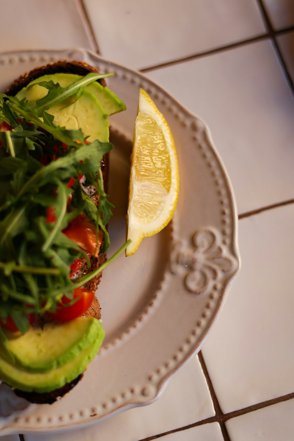 a white plate topped with a sandwich and a slice of lemon