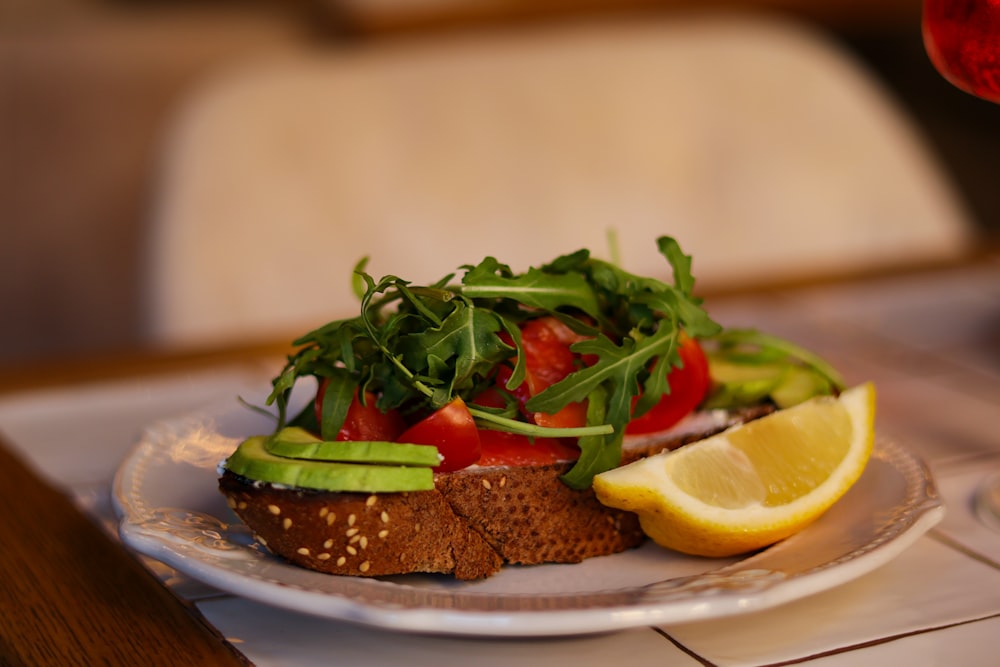 a white plate topped with a sandwich and a slice of lemon