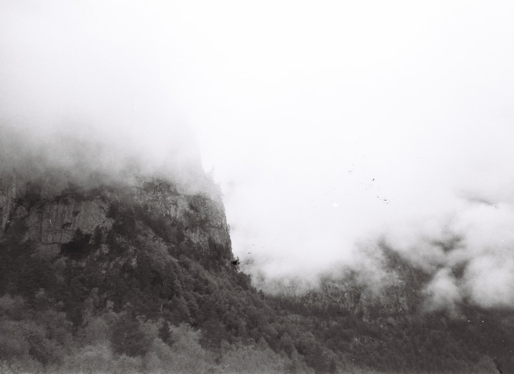 a black and white photo of a foggy mountain