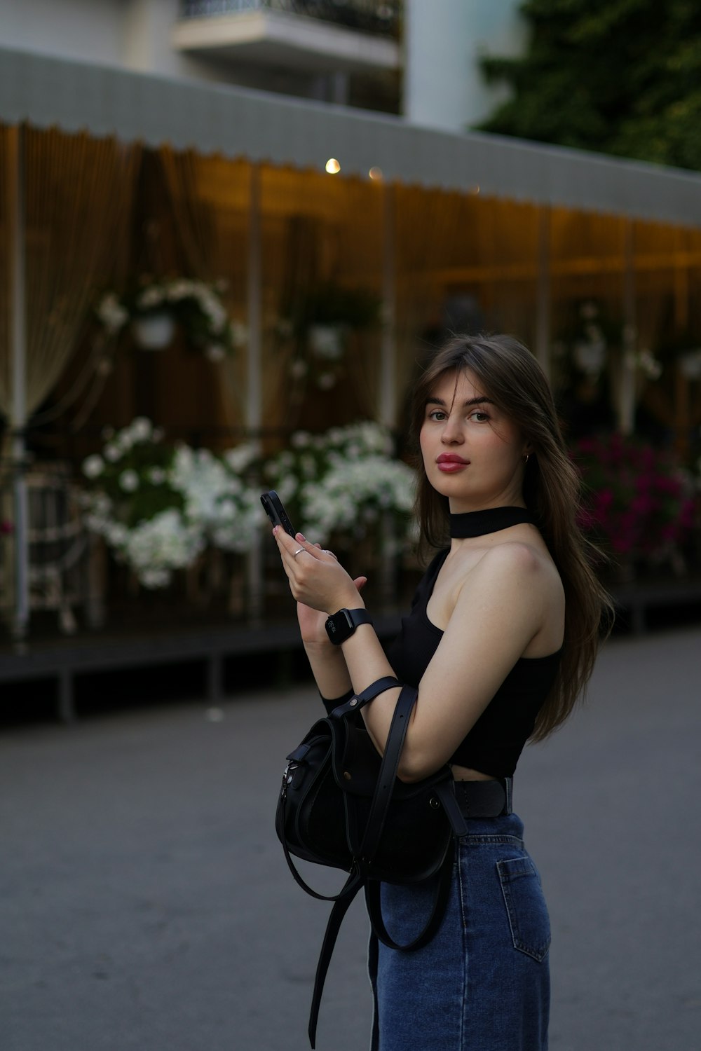 a woman in a black top is holding a cell phone