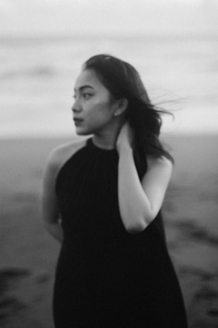 Black and white portrait of a thoughtful woman looking out to the sea, symbolizing depth and reflection.