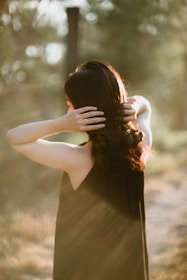Hands applying nourishing hair oil to long, healthy hair in soft natural light.