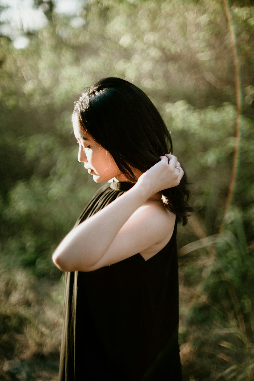 a woman in a black dress standing in a forest