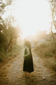 A peaceful outdoor scene with a woman walking barefoot on grass at dawn.
