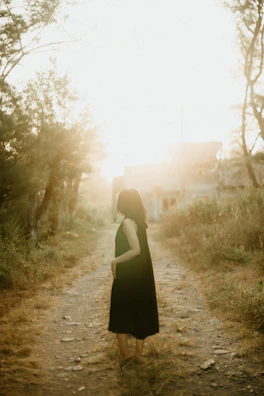 A peaceful outdoor scene with a woman walking barefoot on grass at dawn.