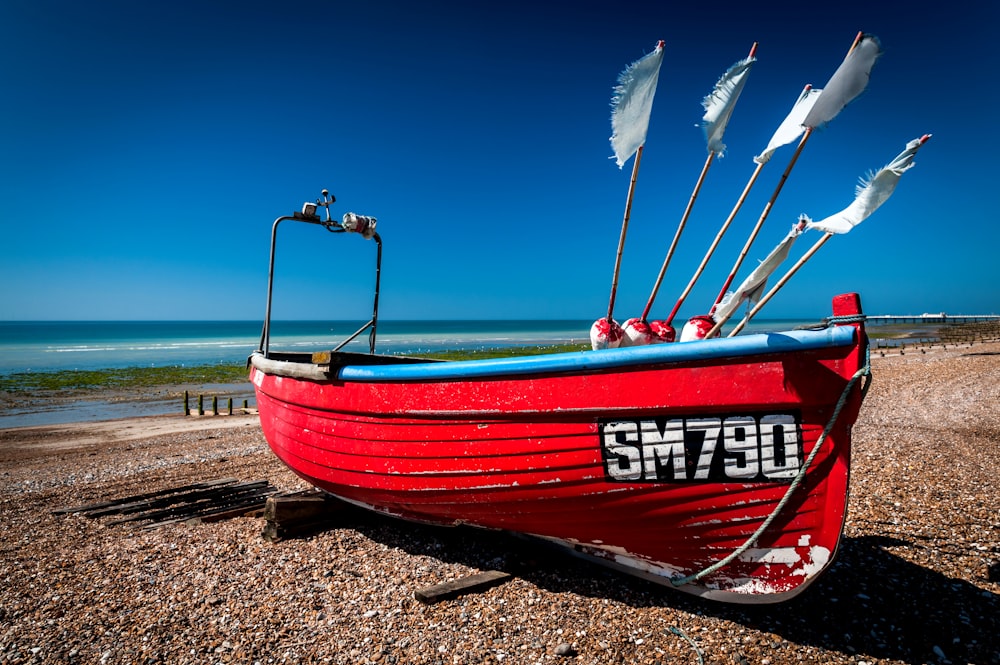 Un bateau rouge assis au sommet d’une plage de sable