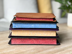 A stack of the book alongside a journal and colored pencils, all set on a two-toned beige and brown surface.