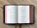 An open book with the title '1 Chronicles' at the top of the left page, displaying several columns of text. The book is placed on a wooden surface, and a bookmark ribbon is visible.