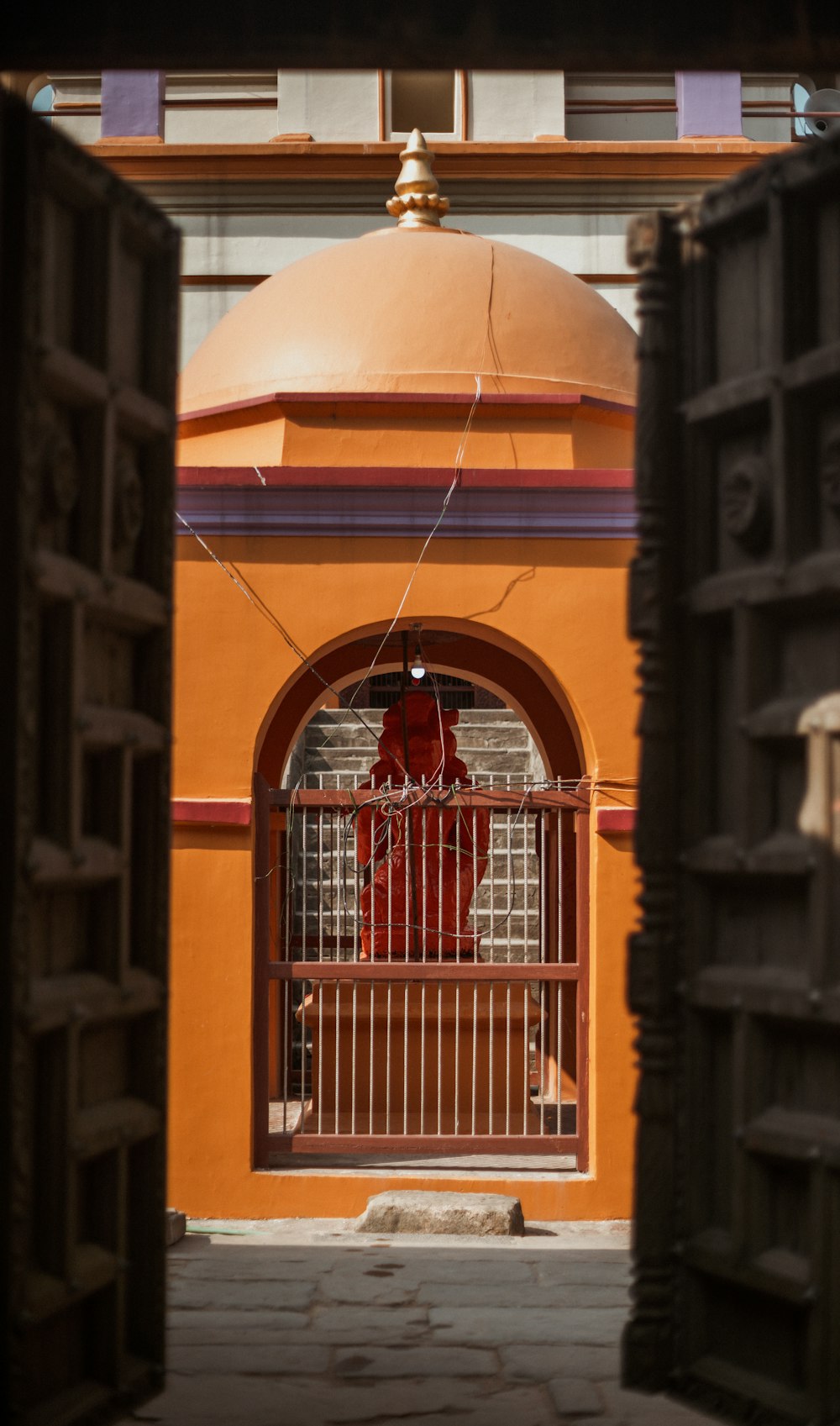 um hidrante vermelho sentado em frente a um prédio amarelo