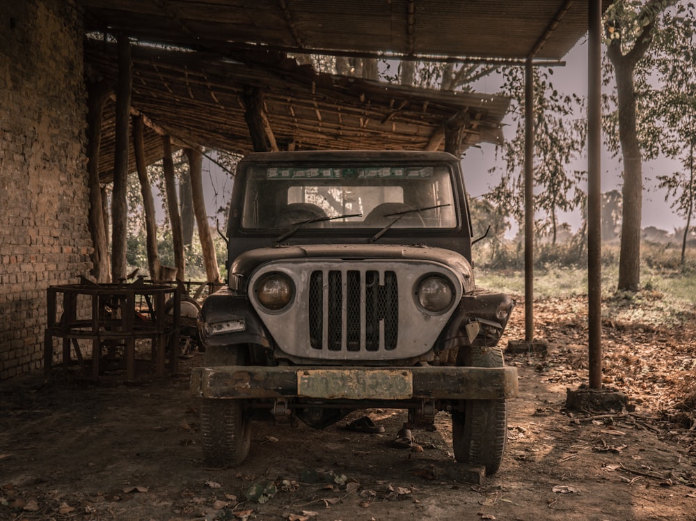 an old jeep is parked under a shelter