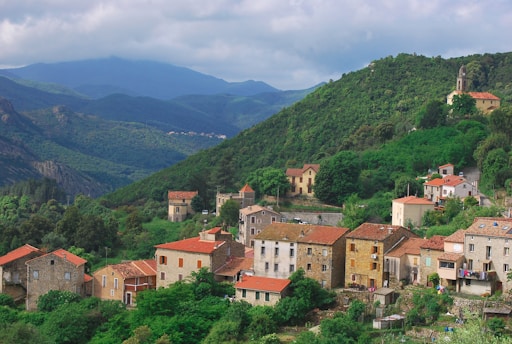 a small village on a mountain side with mountains in the background