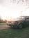 A gleaming vintage car parked beside a charming countryside inn at sunset.