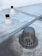 A rooftop surface with a metal drain cover and pipes protruding from the surface. The drain cover has vertical slats surrounding it. The surface appears to be slightly worn with some darker patches and dirt marks.