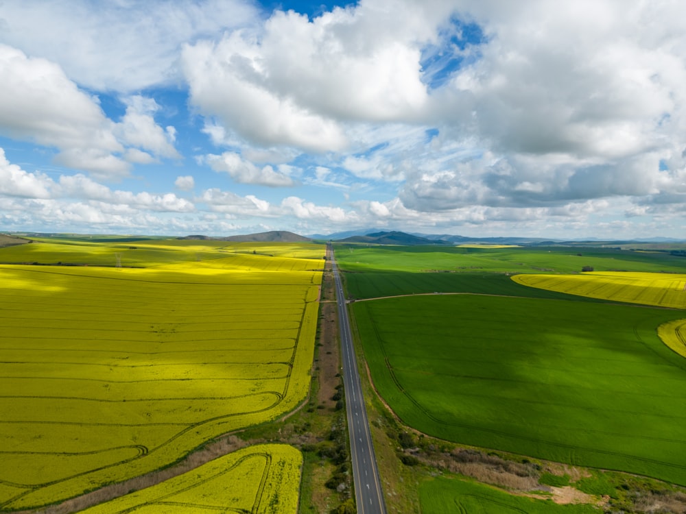 an aerial view of a road running through a green field