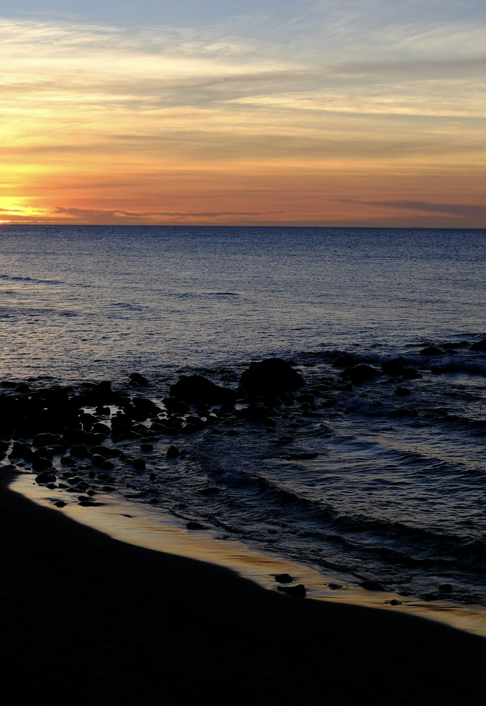 the sun is setting over the ocean on the beach