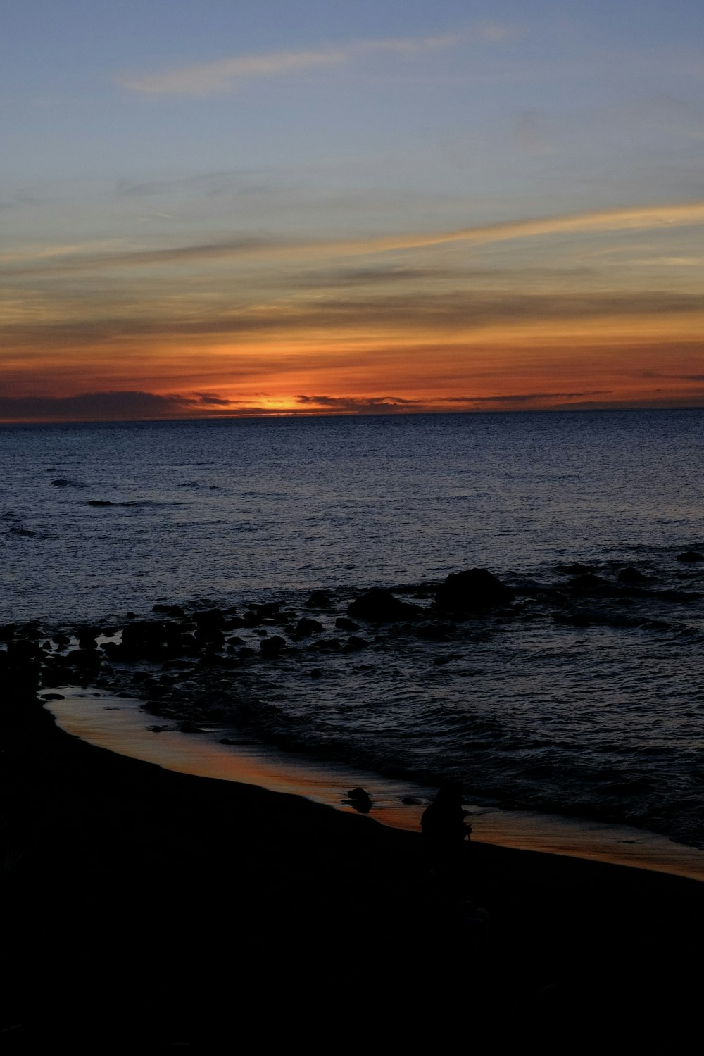 the sun is setting over the ocean on the beach