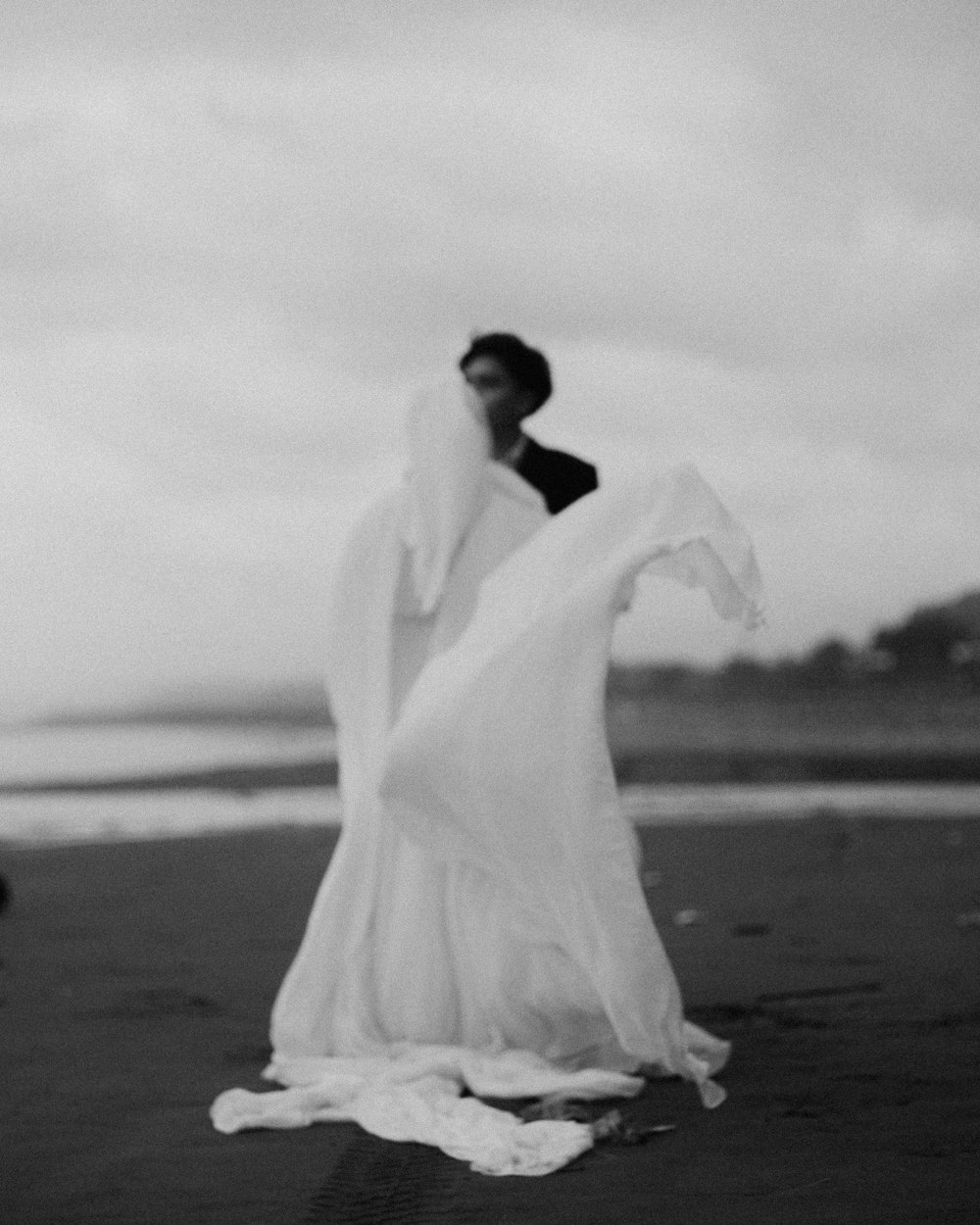a black and white photo of a bride and groom on the beach